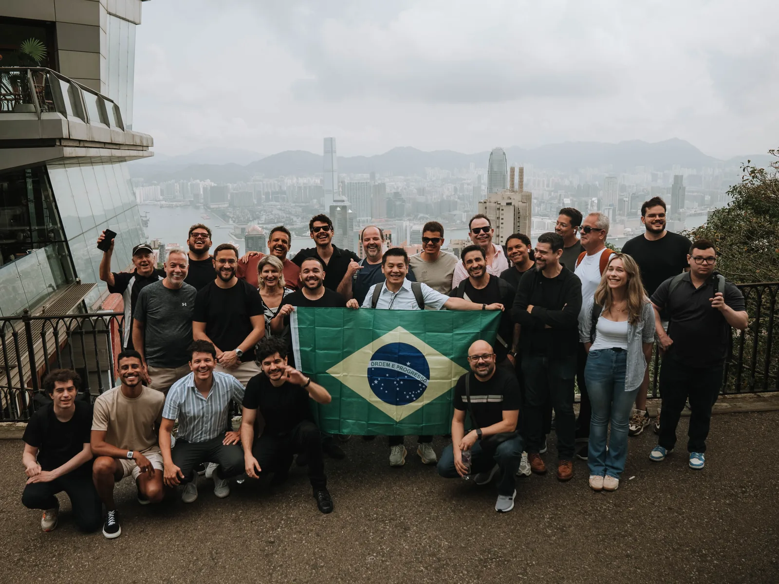 Delegação da AUVP Experience com a bandeira do Brasil, diante da paisagem de Hong Kong.